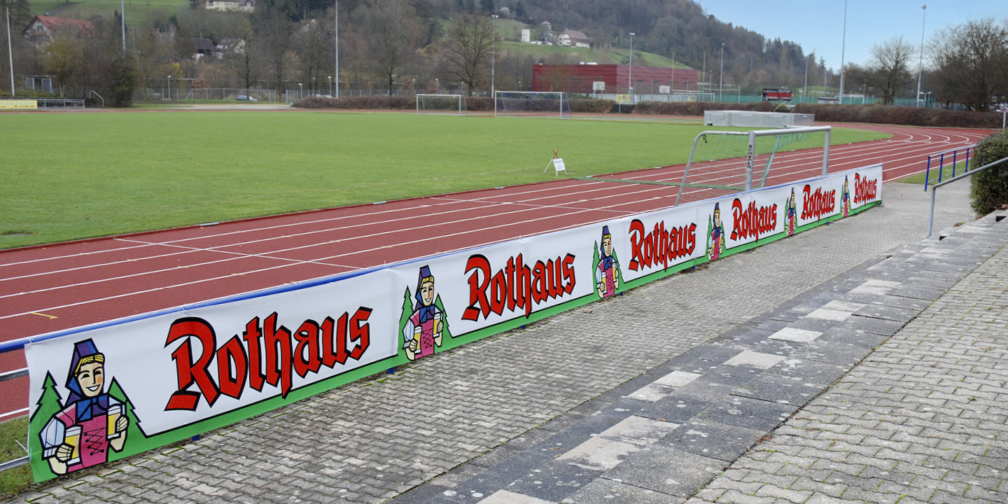 Banner-Werbung aus einem Sportplatz mit Vliesbanner, hier für die Rothaus Brauerei